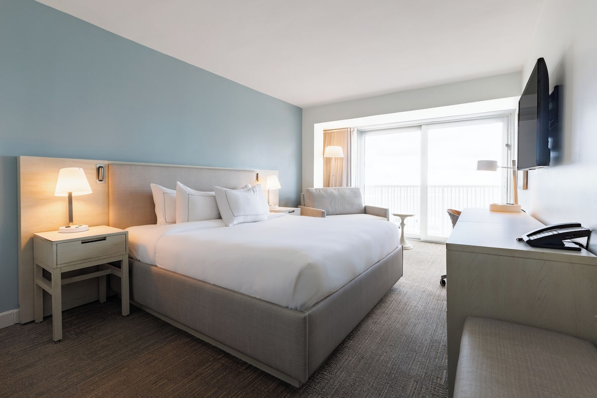 A hotel room with a bed, bedside tables, a desk, and a TV.