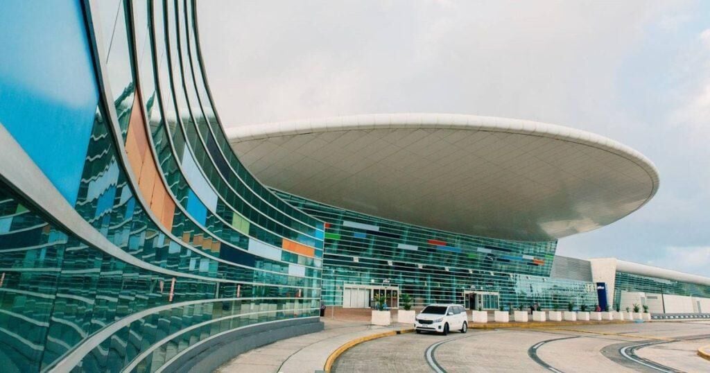 A modern building with a curved glass facade and a large overhanging roof.