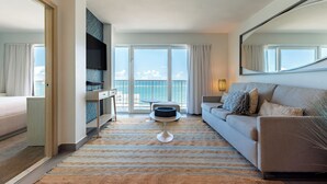 Et moderne hotelværelse med balkon, sofa, TV og spiseplads.