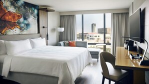 Une chambre d’hôtel moderne, dotée d’un grand lit, d’un bureau et offrant une vue sur la ville.