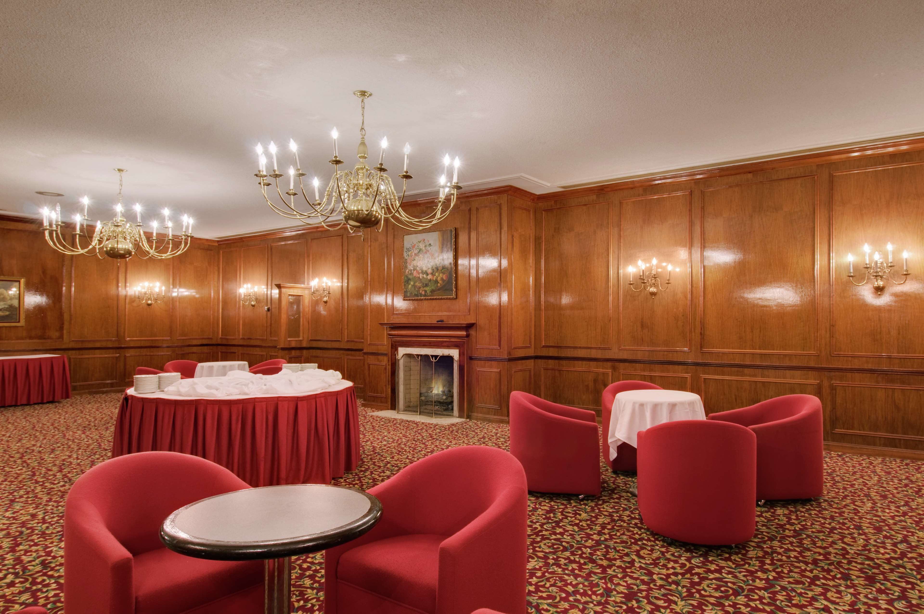 A conference room with red chairs, a round table, and a chandelier.