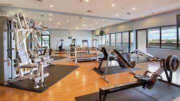 A gym with cardio machines, weightlifting equipment, and dumbbells.