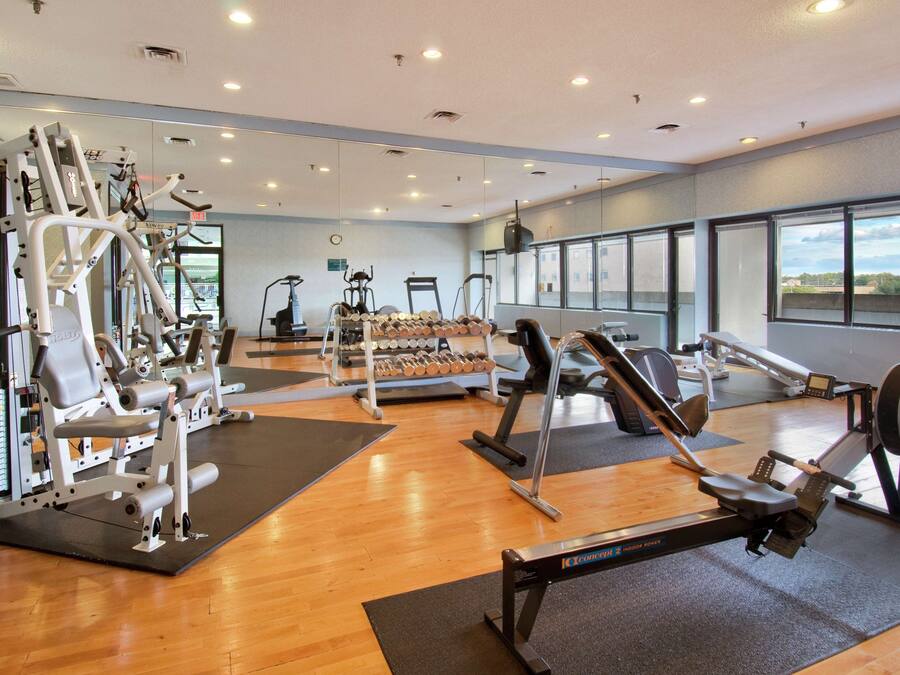 A gym with cardio machines, weightlifting equipment, and dumbbells.