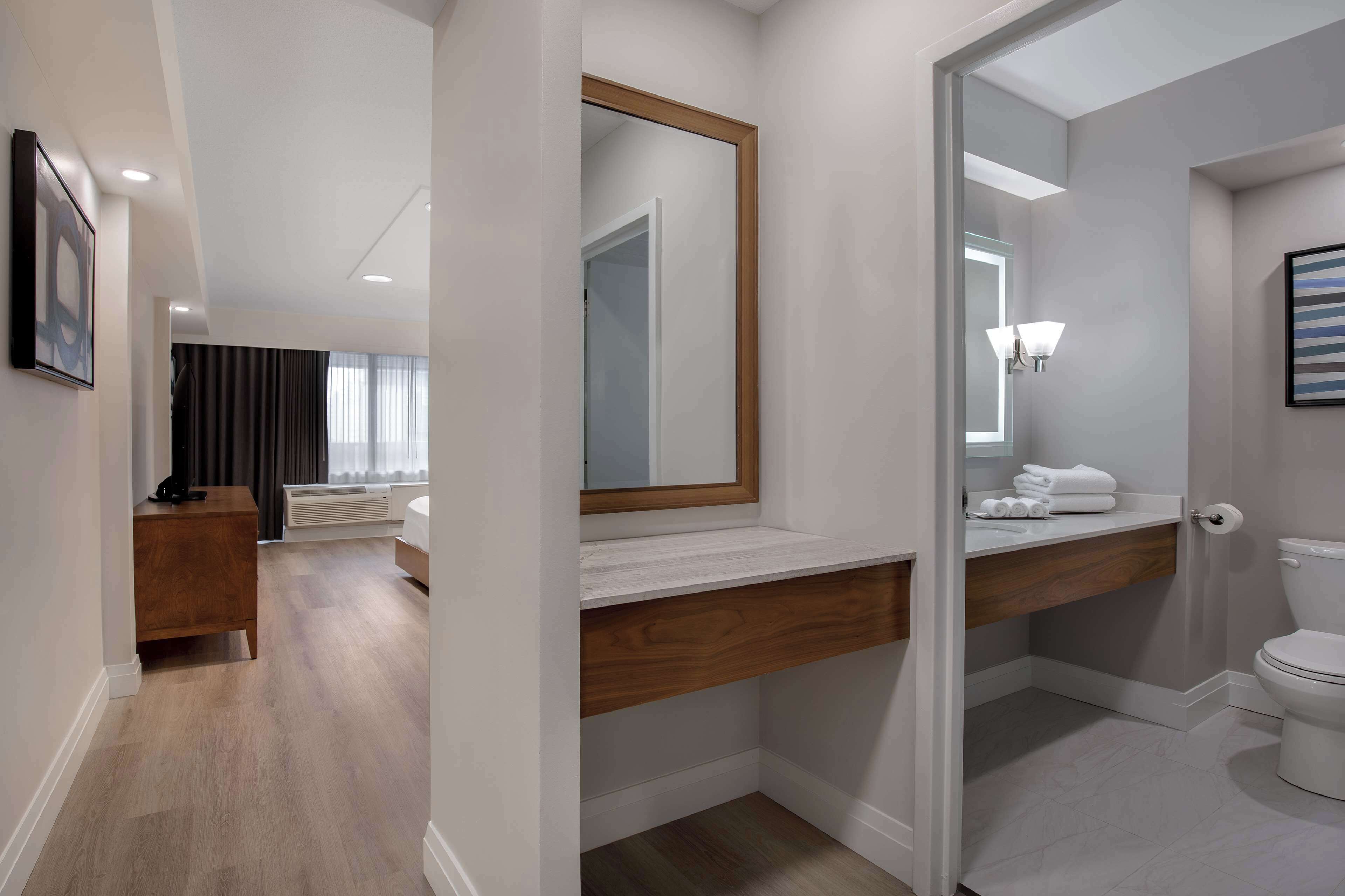 A modern bathroom with a wooden vanity, a large mirror, and a toilet.