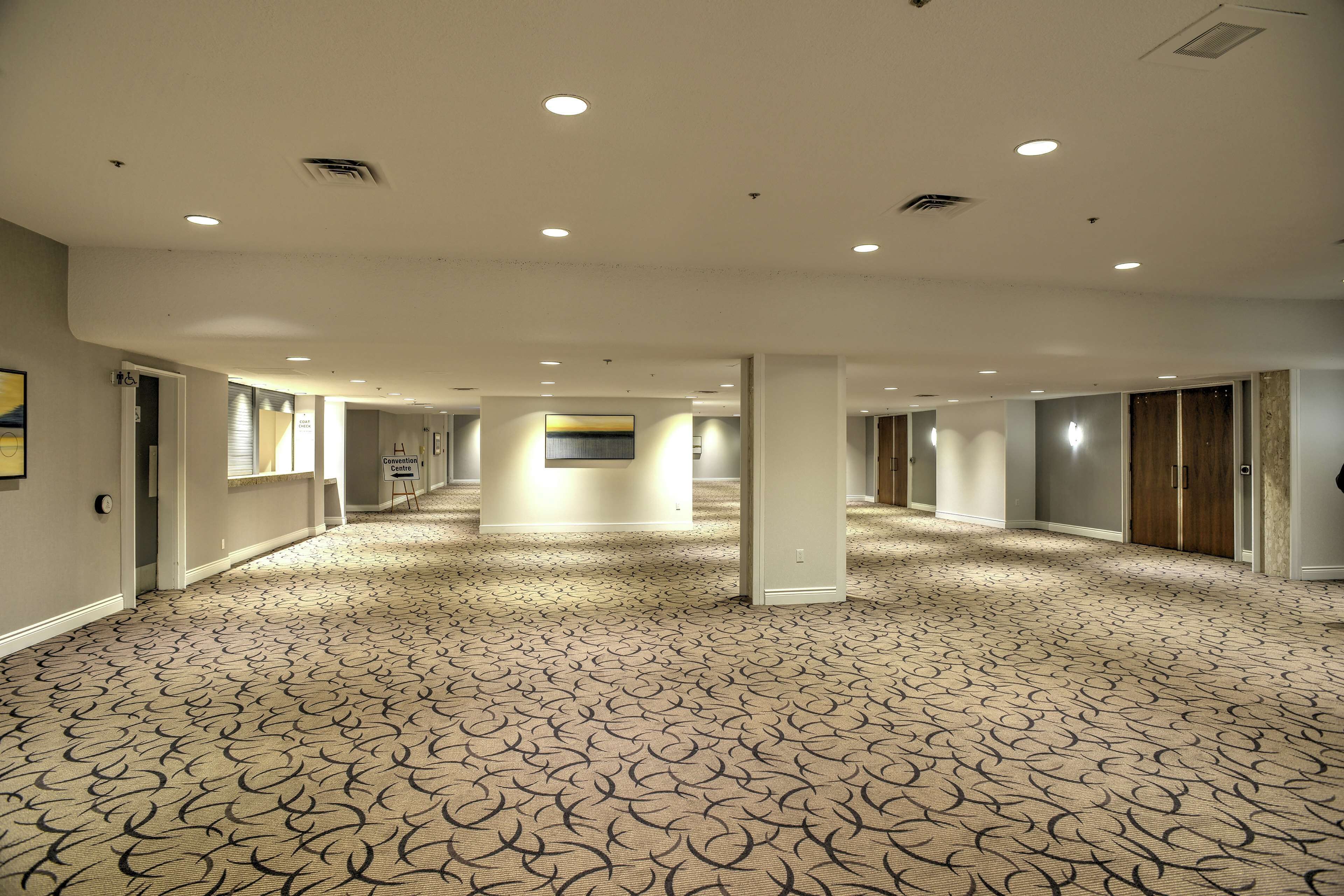 Corridoio di un hotel con tappeto decorato, illuminazione a incasso e porte che danno sulle camere.