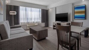 A modern living room with a sofa, coffee table, TV, and dining area. - DoubleTree by Hilton Hotel London Ontario (London)