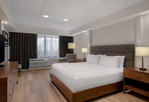 A hotel room with a large bed, bedside tables, a desk, a chair, and a window with curtains. - DoubleTree by Hilton Hotel London Ontario (London)