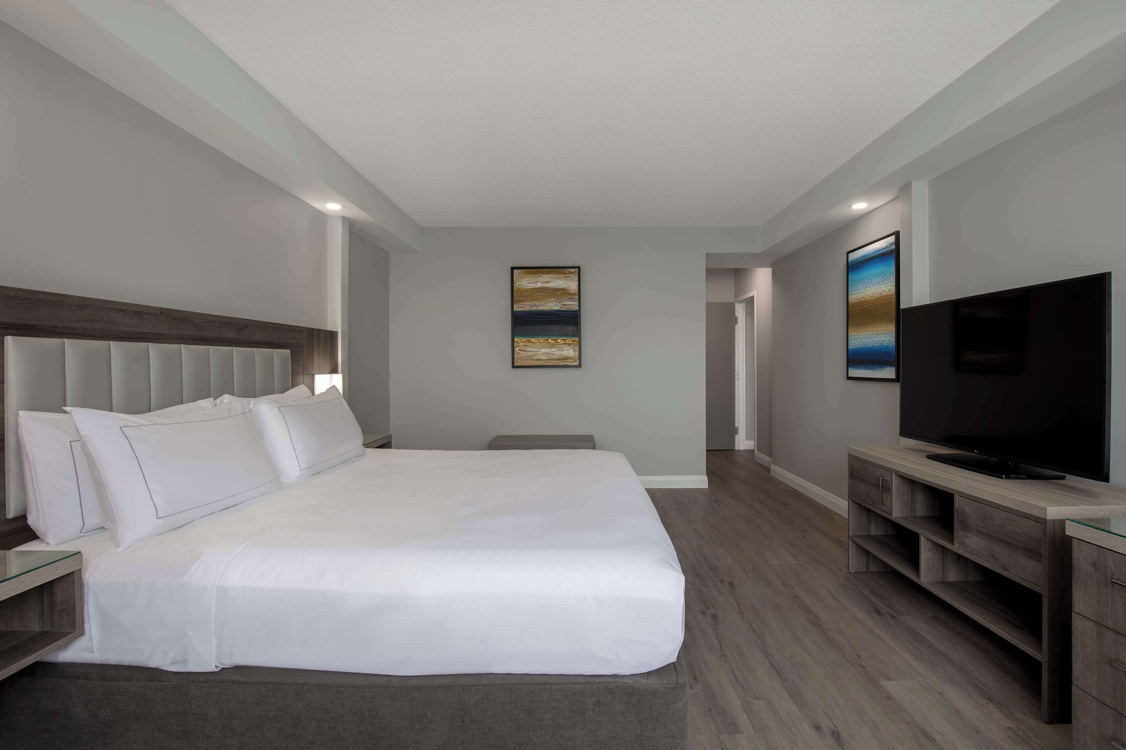 A modern hotel room with a large bed, a flat-screen TV, and a minimalist design.