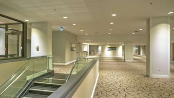 A hotel corridor with a carpeted floor, glass railings, and recessed lighting.