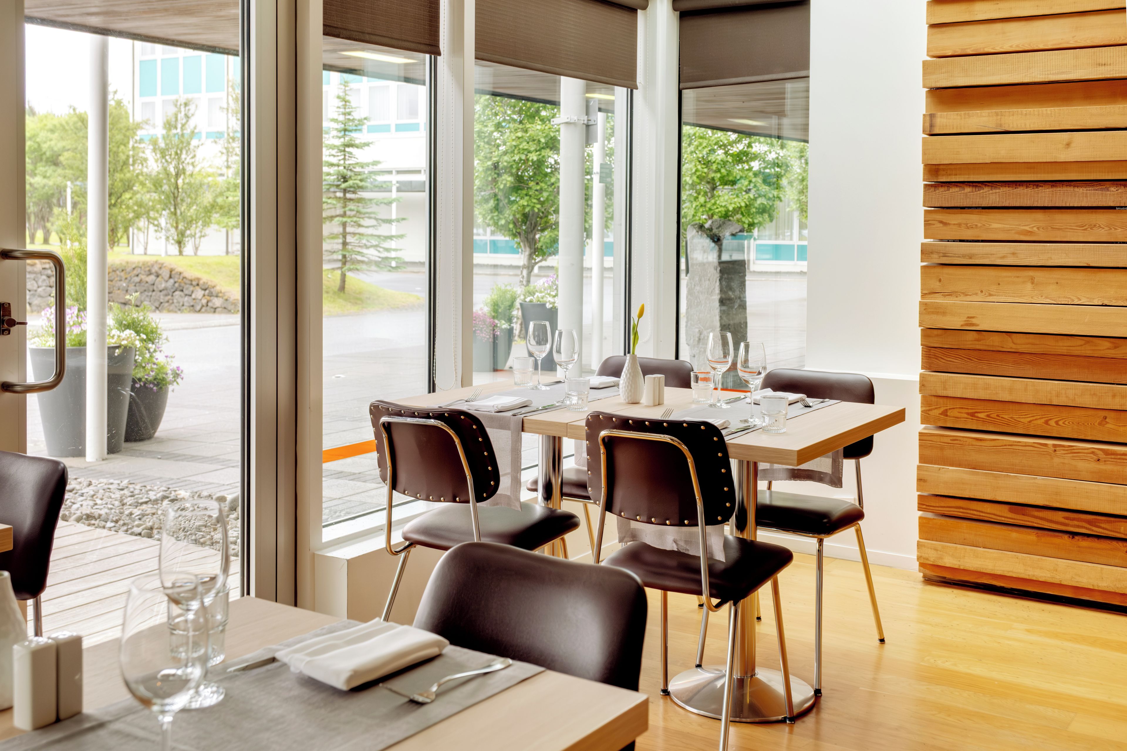 A dining area with a table set for two, chairs, and a view of the outdoors.