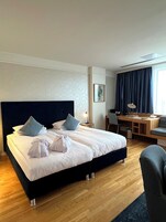 Una habitación de hotel con una cama grande, un escritorio y una silla.