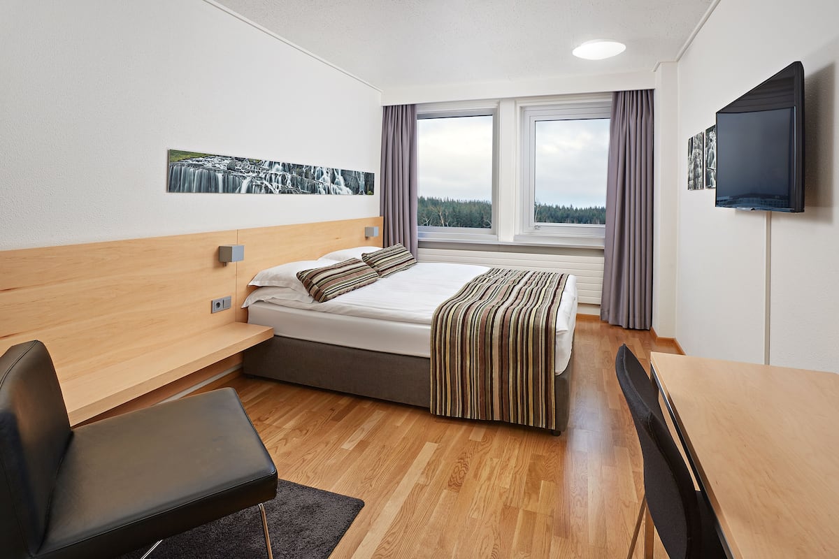 Une chambre d’hôtel moderne équipée d’un lit, d’un bureau, d’une chaise et d’un téléviseur.