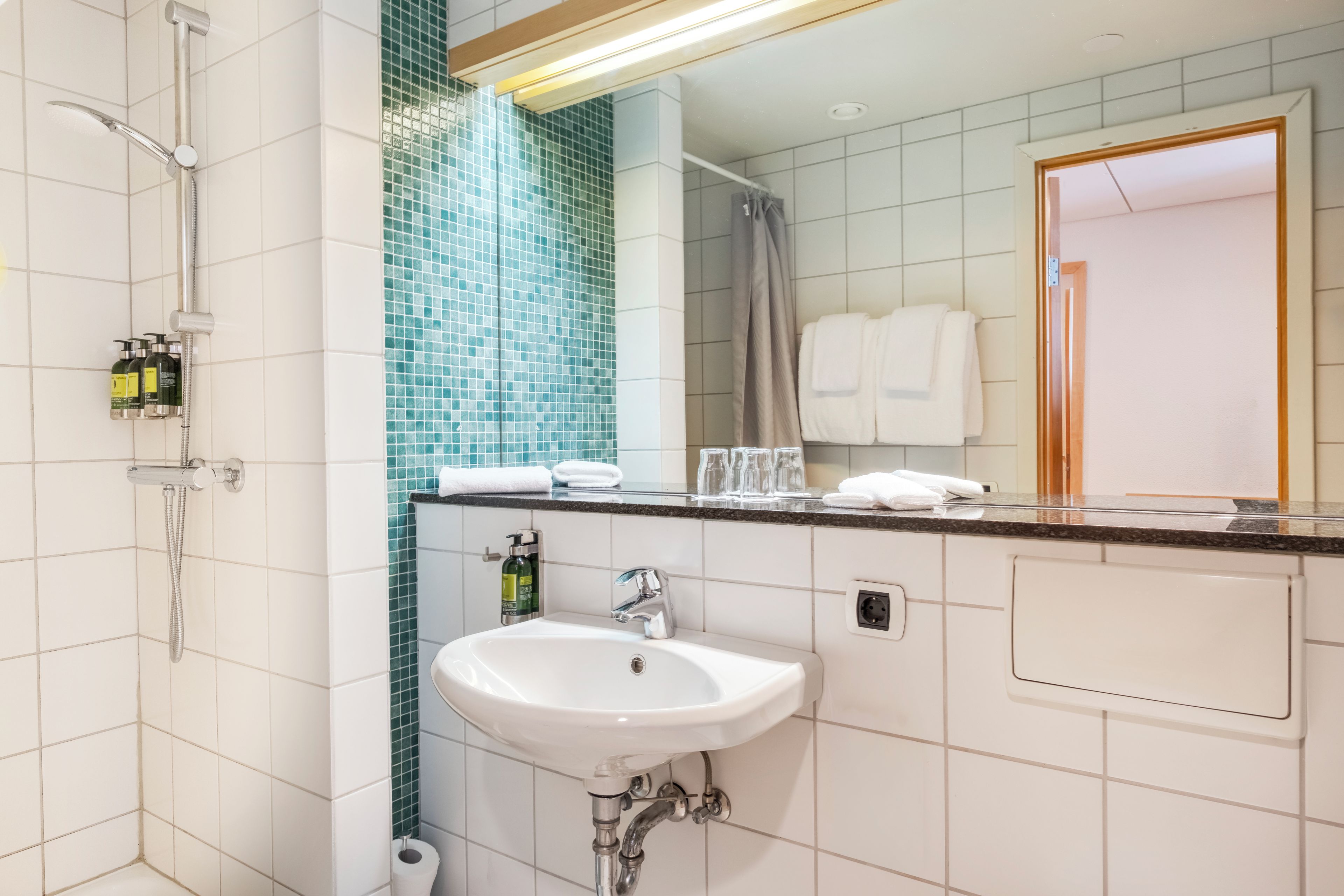 Un baño moderno con ducha, lavabo y espejo.
