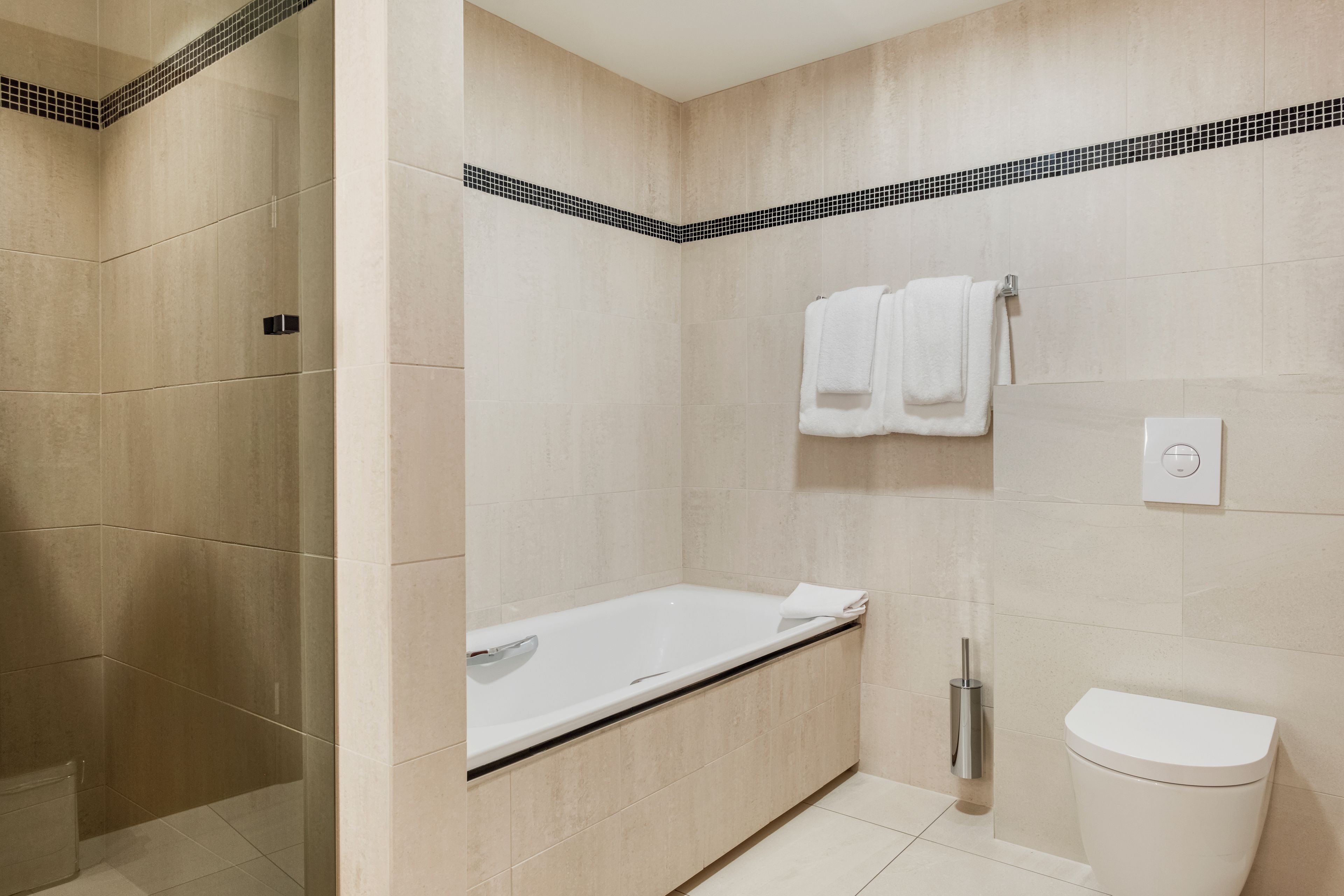 A modern bathroom with a bathtub, toilet, and shower area.