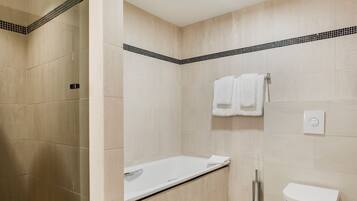 A modern bathroom with a bathtub, toilet, and shower area.