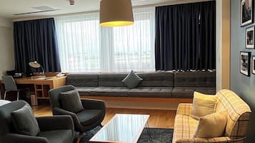 A modern living room with a sofa, armchairs, a coffee table, and a desk.