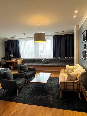 A modern living room with a sofa, armchairs, a coffee table, and a desk.