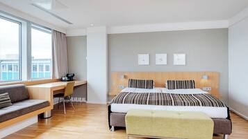 A modern hotel room with a large bed, a desk, and a sofa.