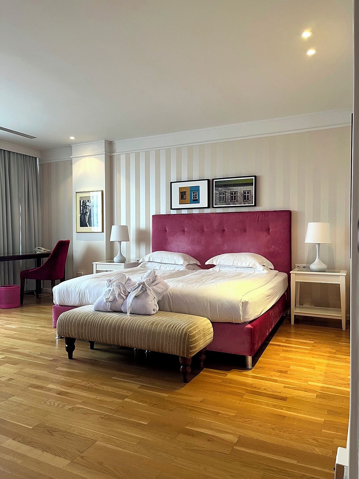 Habitación de hotel con una cama grande, una mesita de noche, una silla y suelo de madera.