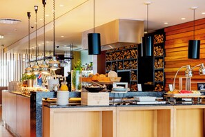 A modern kitchen with wooden cabinets, a central island, and hanging pendant lights. - Hotel Reykjavik Askja (Reykjavik)