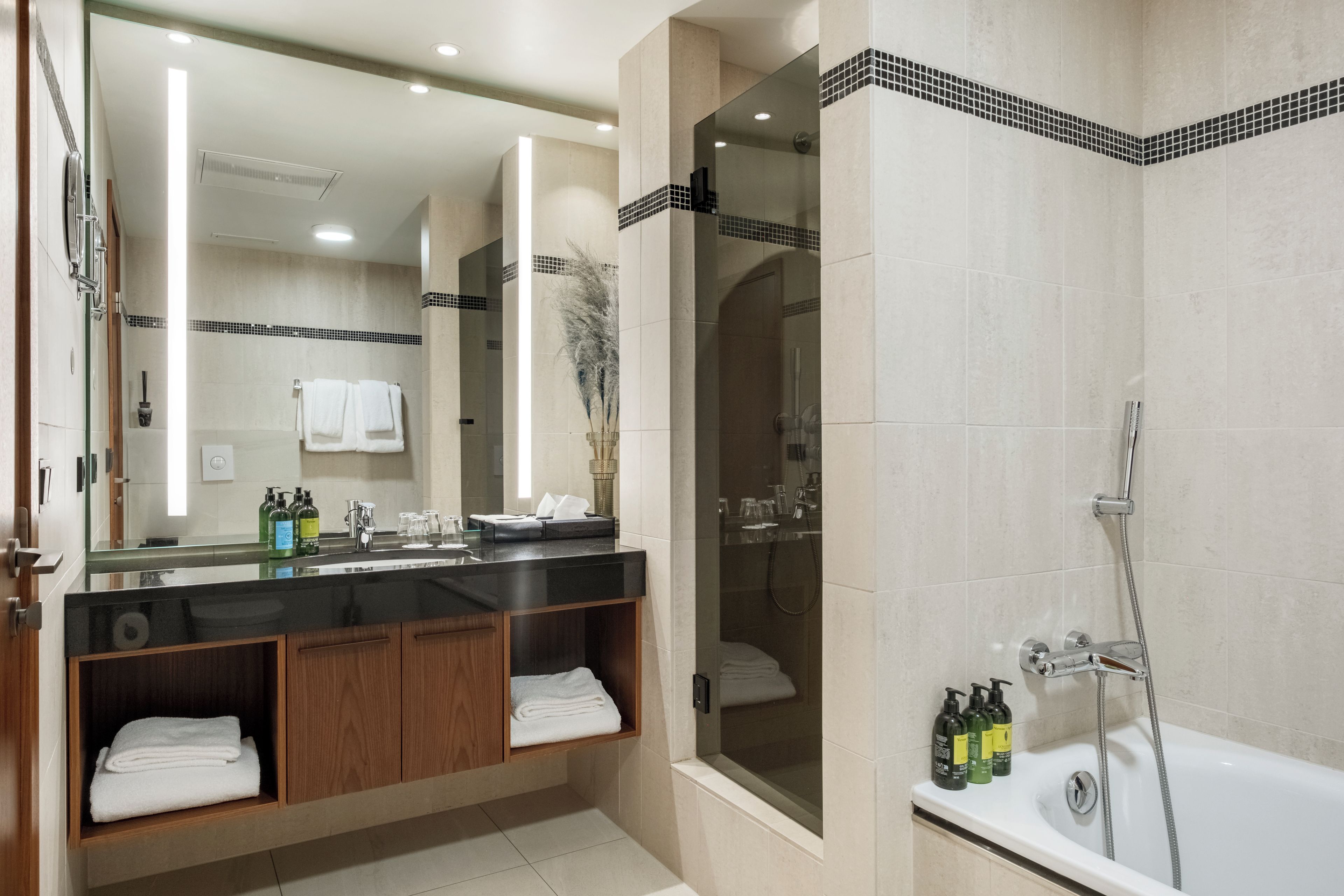 A modern bathroom with a large mirror, a bathtub, and a shower area.