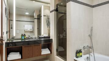 A modern bathroom with a large mirror, a bathtub, and a shower area.