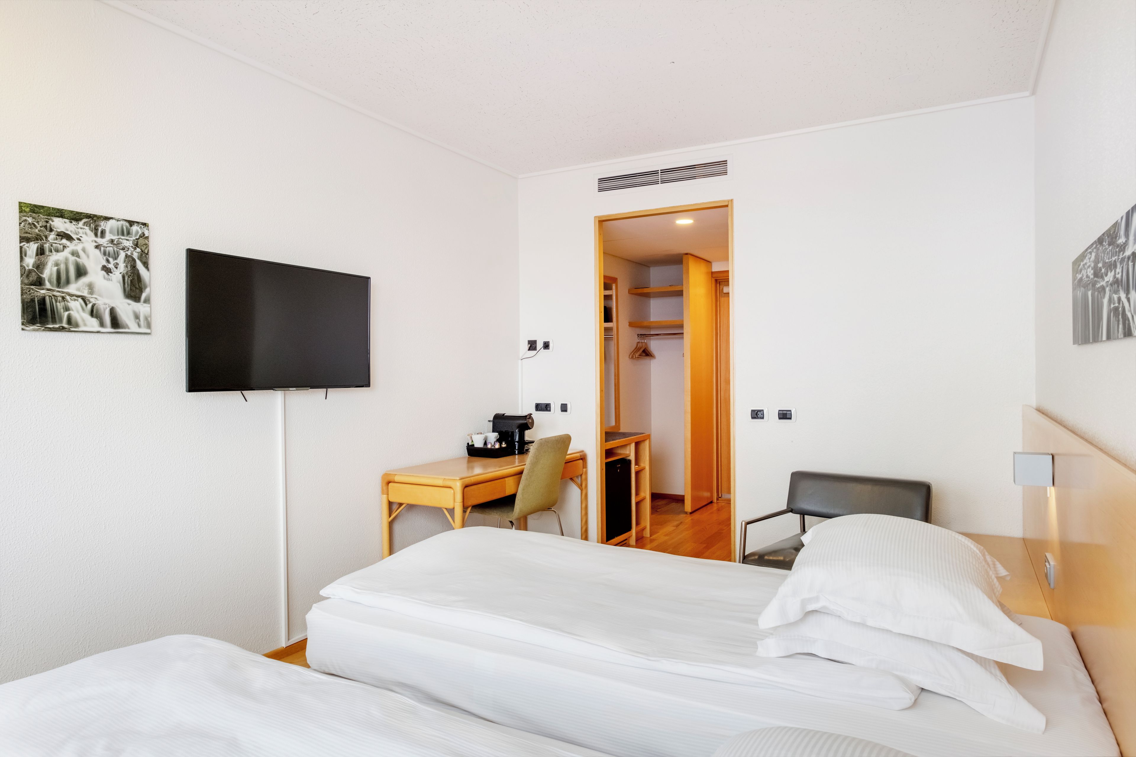 Une chambre d’hôtel équipée d’un lit, d’un bureau, d’une chaise, d’une télévision et d’une armoire.