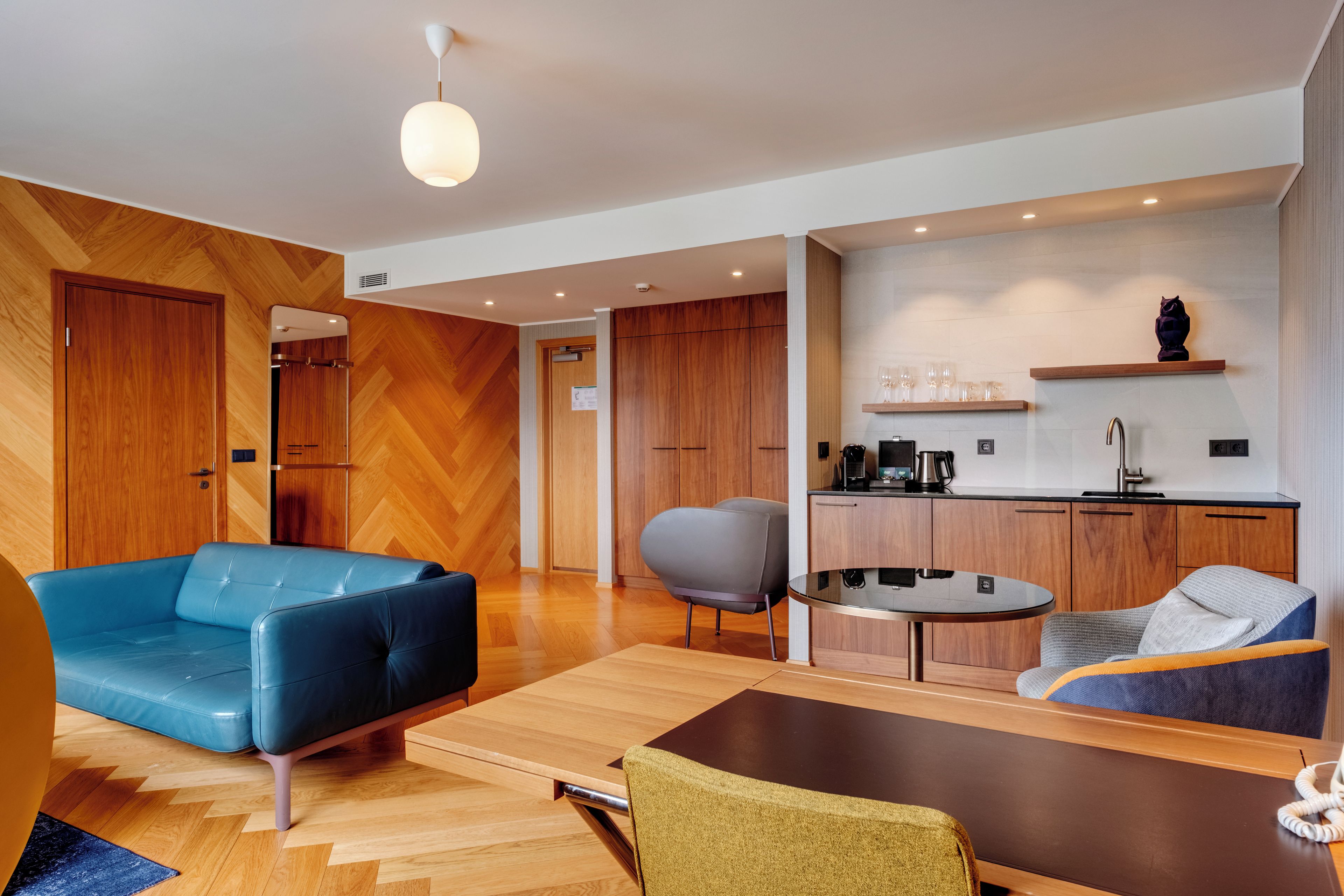 A modern living room with a blue sofa, a grey armchair, and a wooden coffee table.