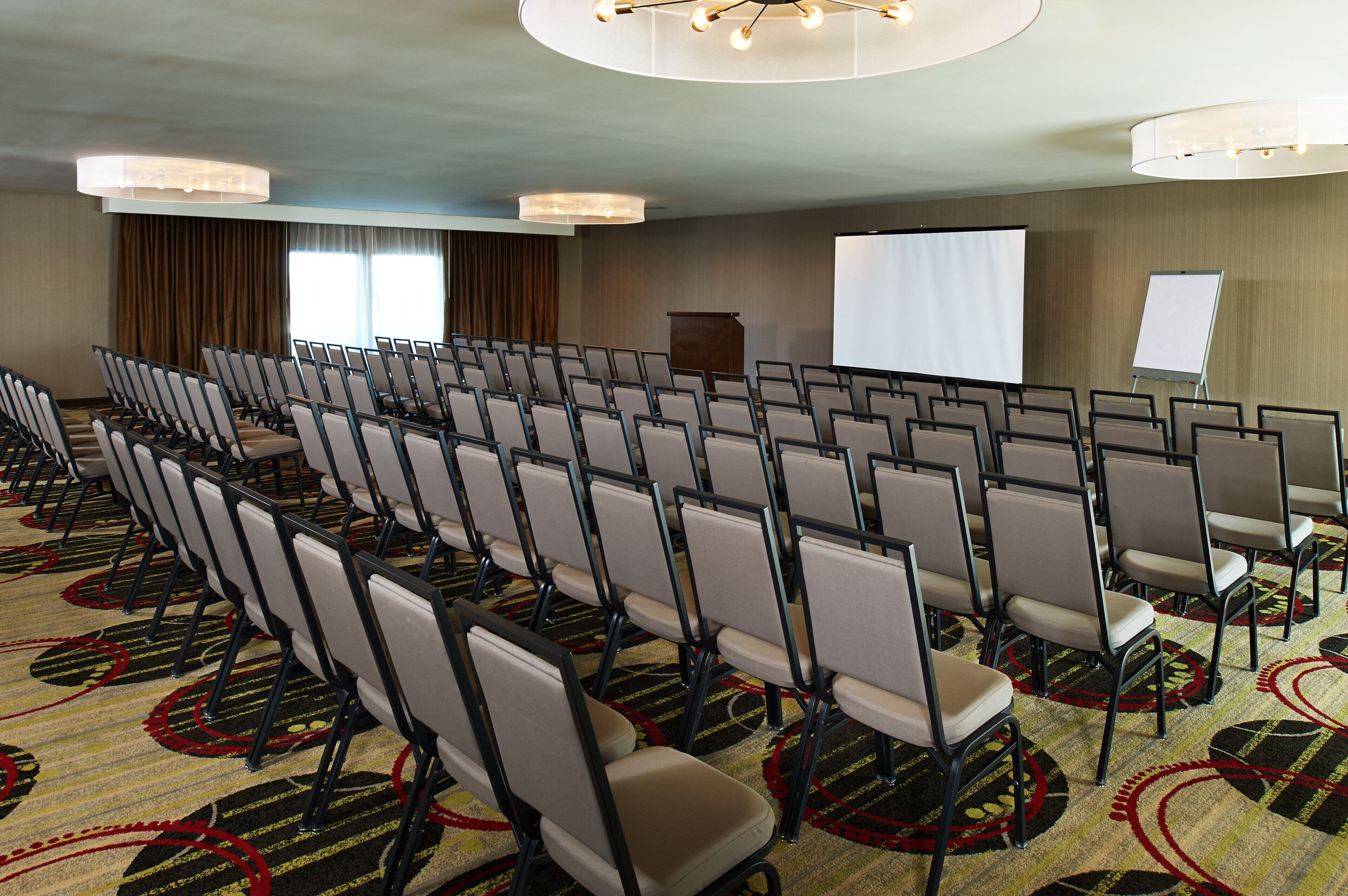 A conference room with rows of chairs, a projector screen, and a whiteboard.