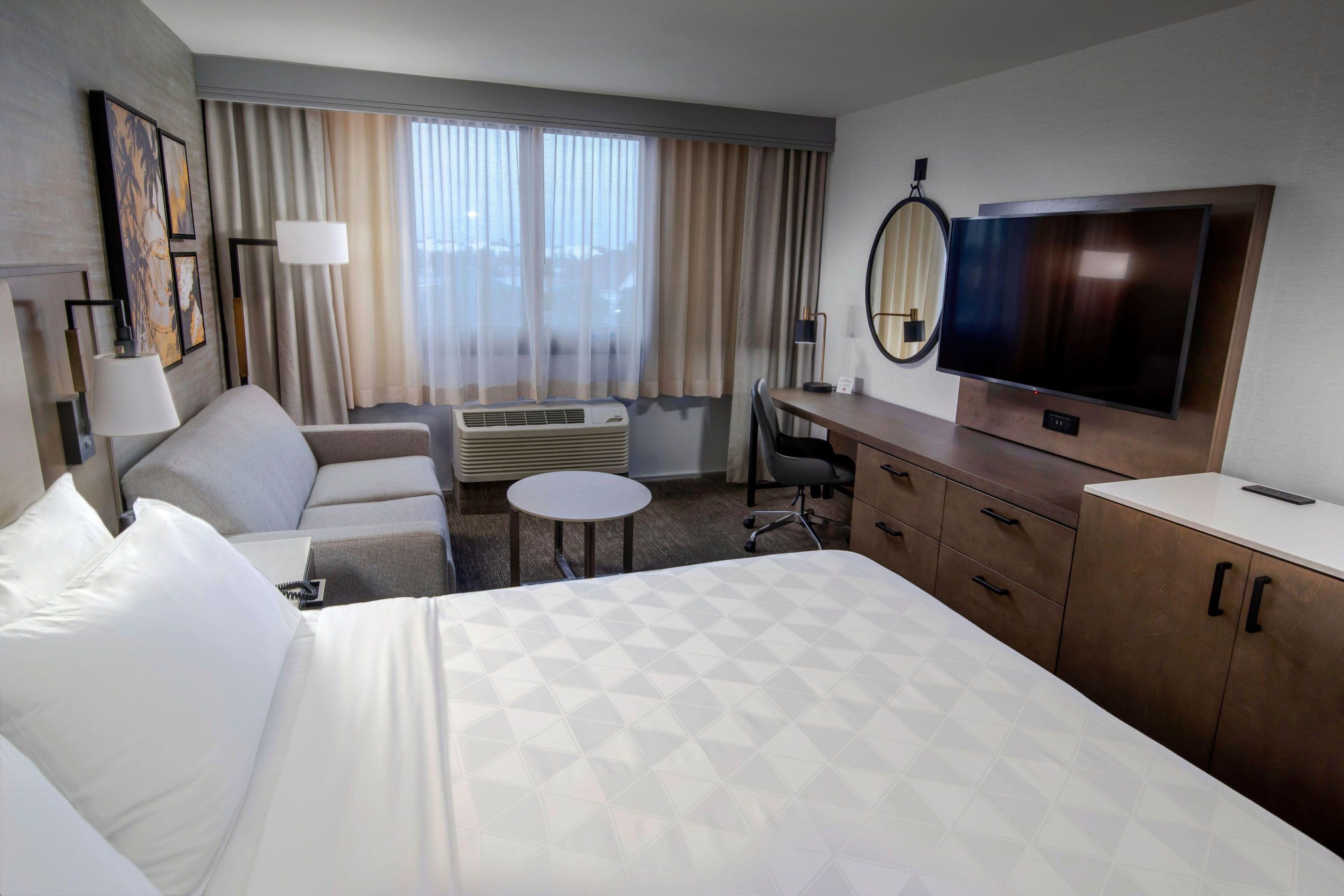 Une chambre d’hôtel équipée d’un lit, d’un bureau, d’une télévision, d’une chaise et d’une petite table.