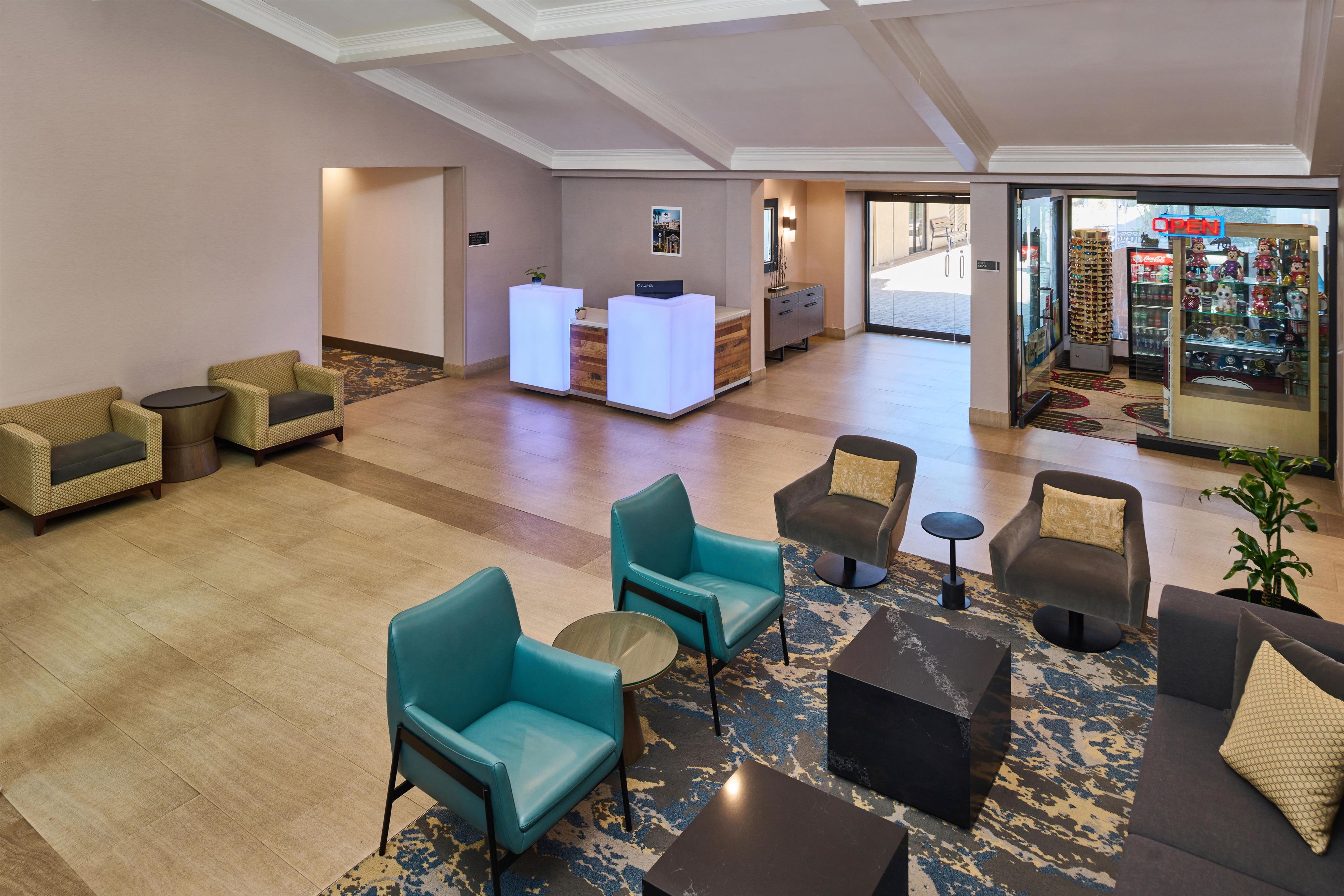 Un vestíbulo de hotel con áreas de descanso, una recepción y un escaparate de vidrio.
