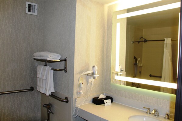 A hotel bathroom with a large mirror, towel rack, and a sink with a vanity. - DoubleTree by Hilton Buena Park (Buena Park)