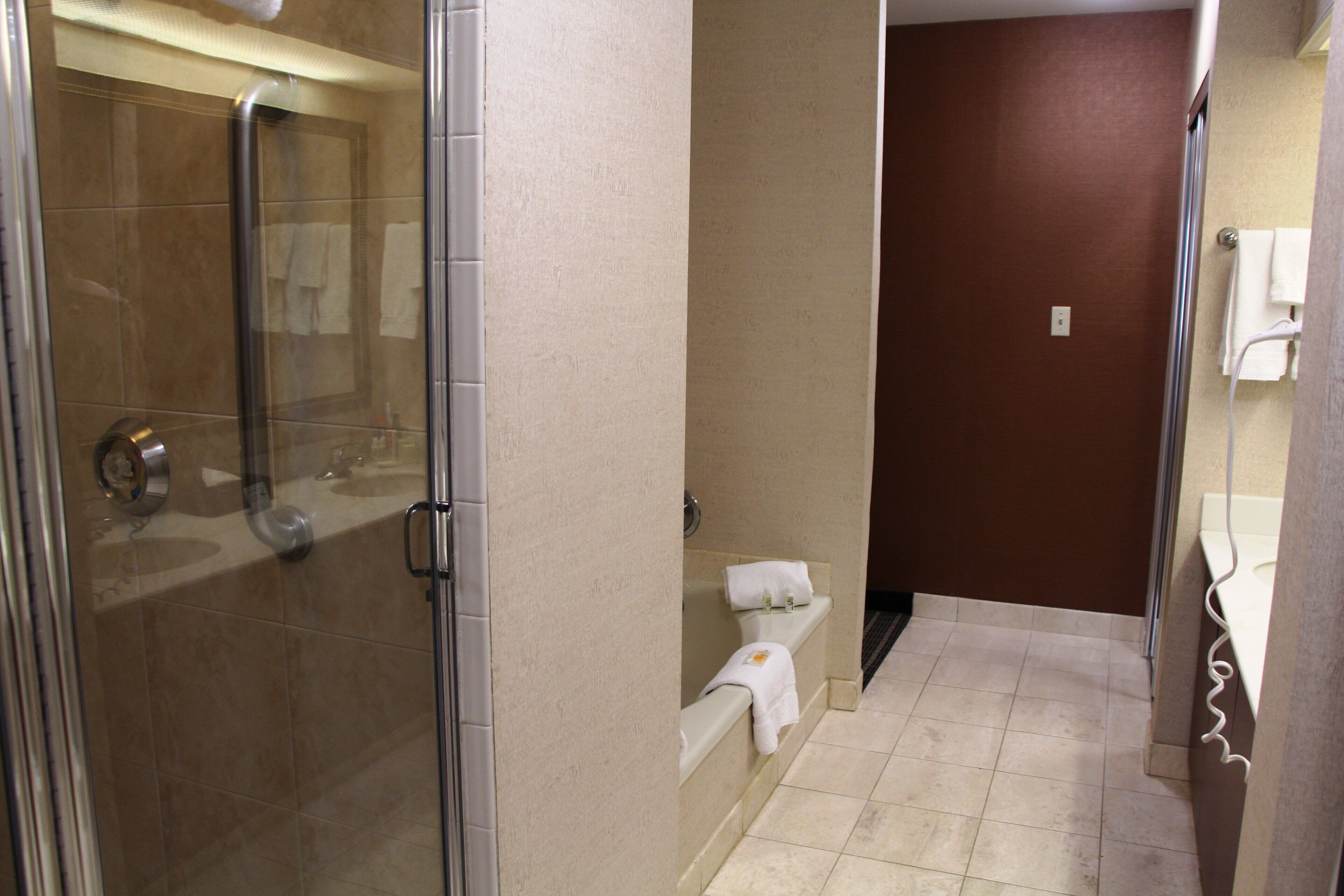 A hotel bathroom with a glass-enclosed shower, a bathtub, and a toilet.