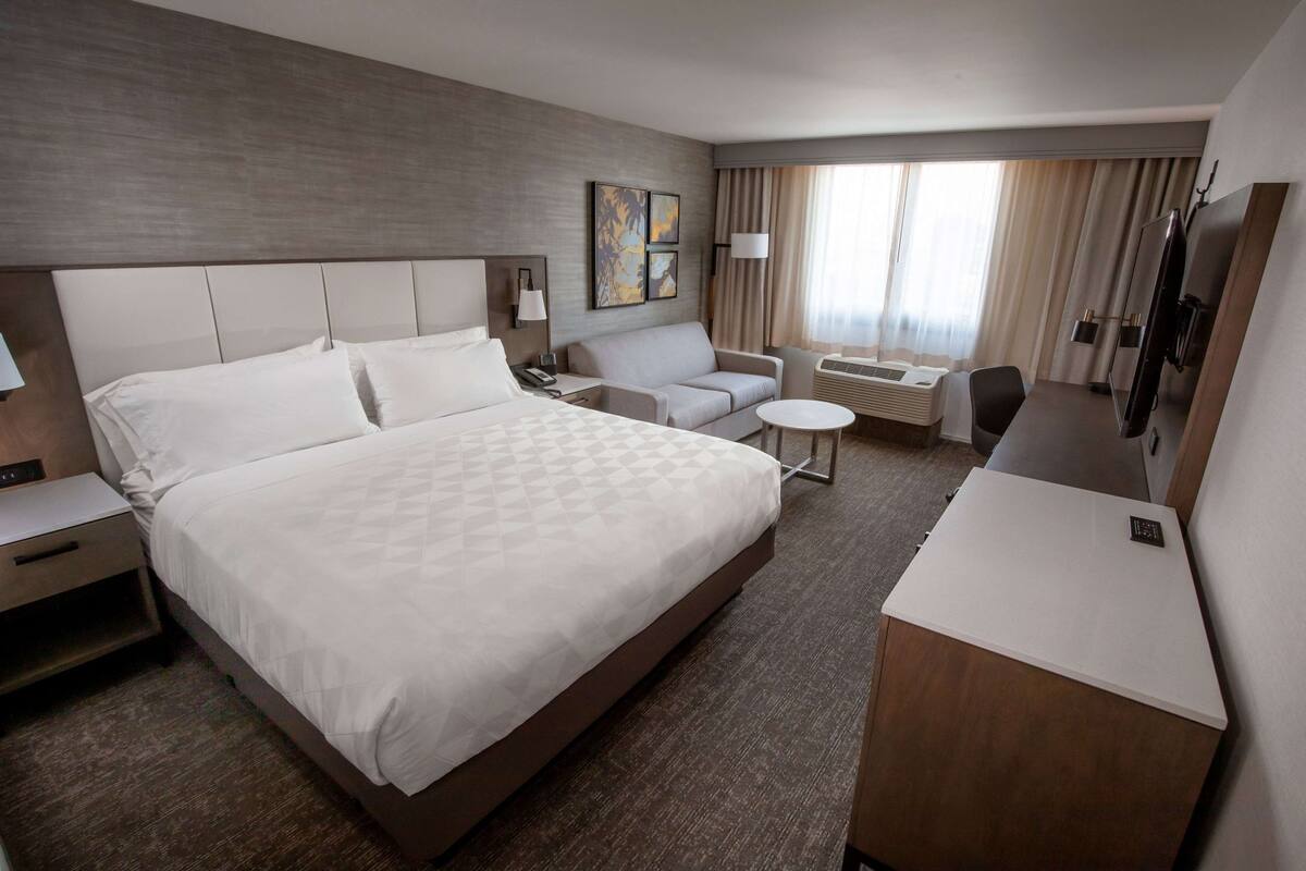Una habitación de hotel con una cama grande, un sofá, un escritorio y un televisor.