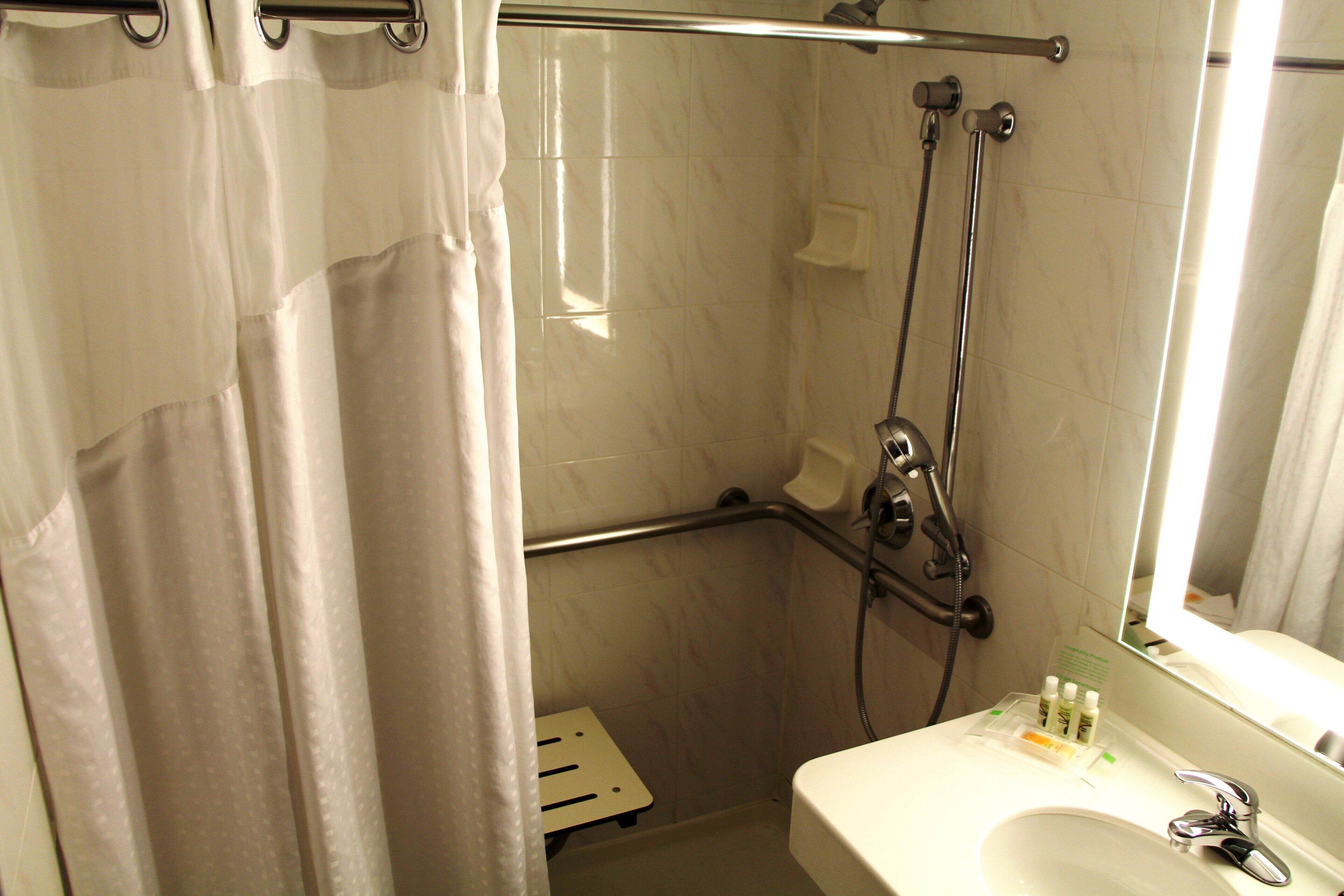 A bathroom with a shower, a sink, and a mirror.