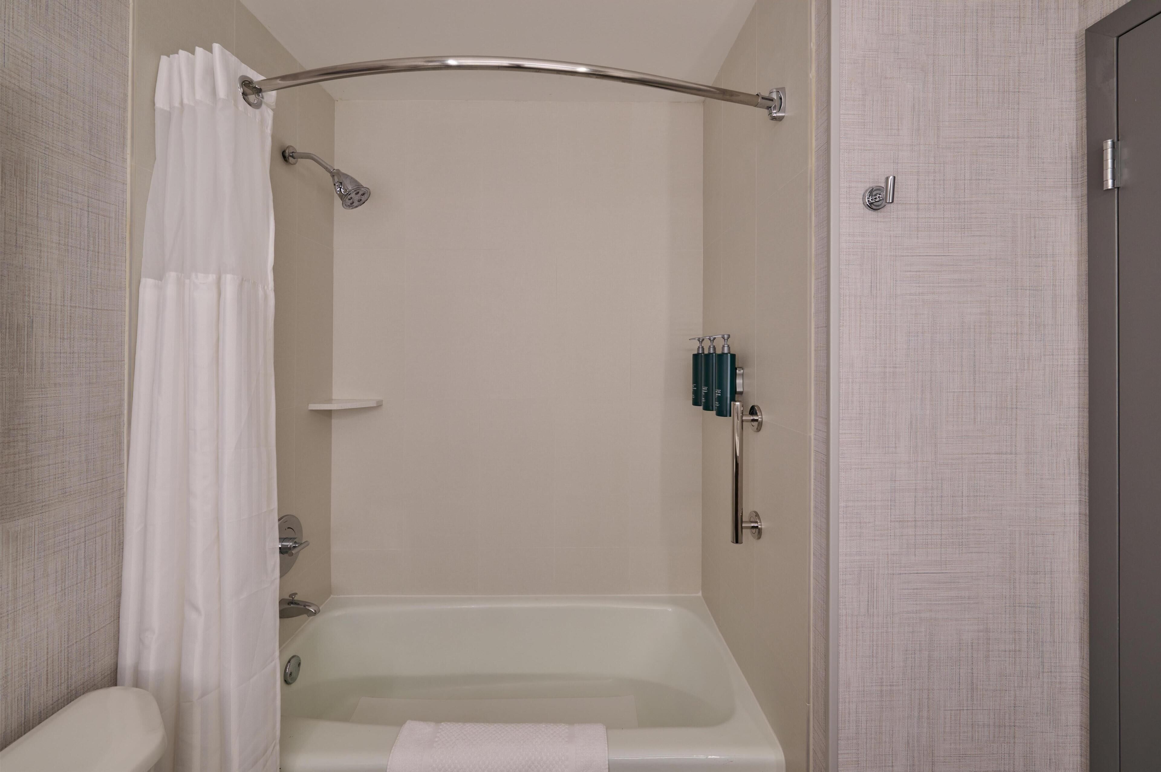 A bathroom with a bathtub, a shower curtain, and a towel rack.