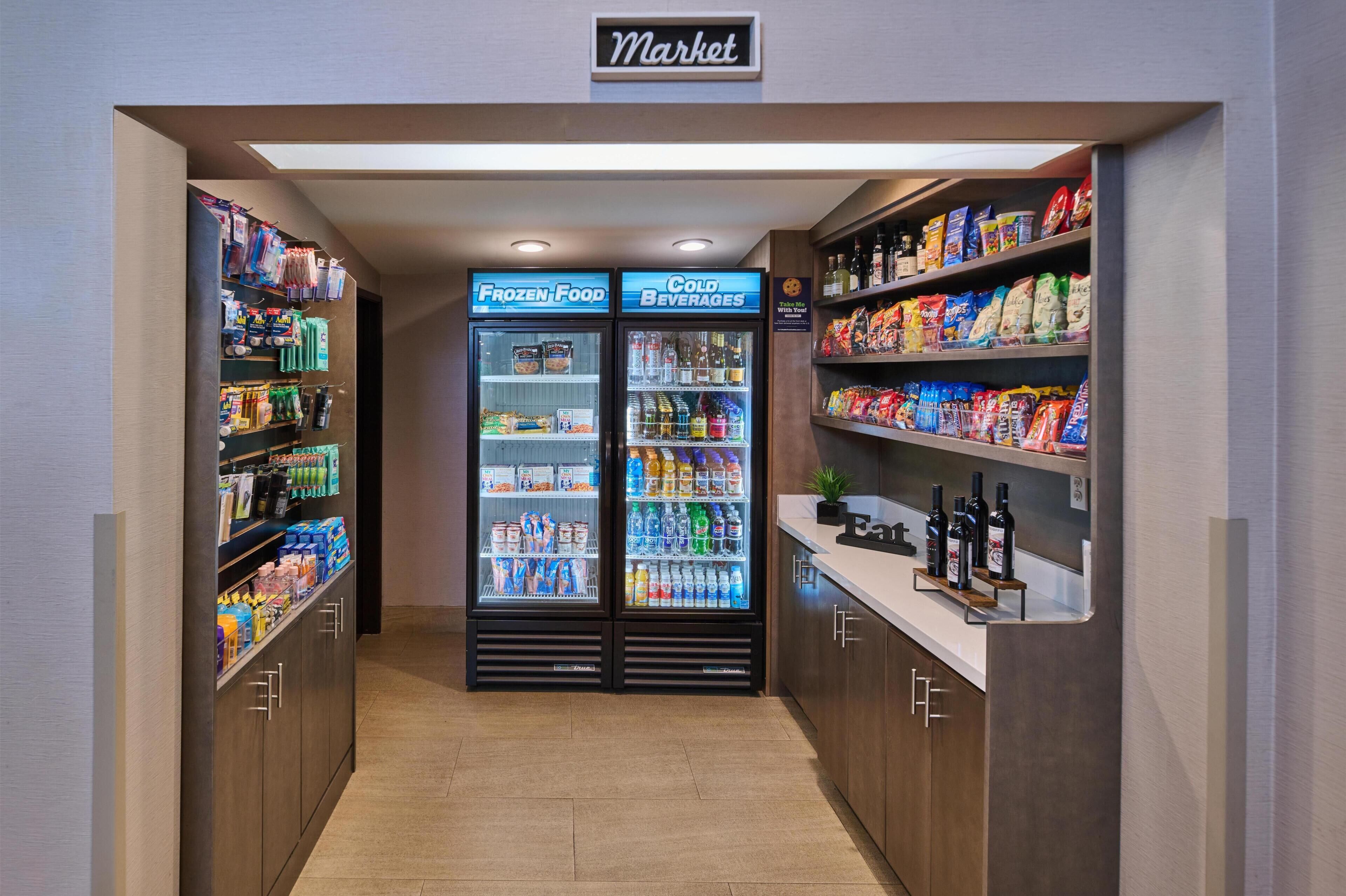 A market area with refrigerated freezers labeled 'Frozen Food' and 'Cold Beverages,' and shelves stocked with snacks and bottled beverages.