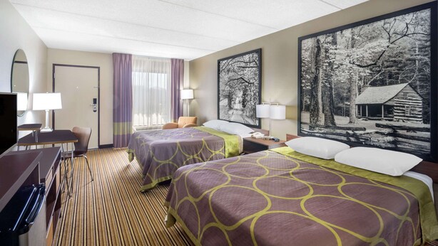 A hotel room with two beds, a desk, a chair, and a TV.