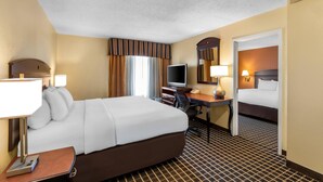 A hotel room with a bed, desk, television, and a door leading to another room. - Comfort Inn & Suites Somerset - New Brunswick (Somerset)