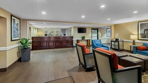 A hotel lobby with a reception desk, seating area with chairs and ottomans, a television mounted on the wall, and a potted plant. - Comfort Inn & Suites Somerset - New Brunswick (Somerset)