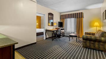 Une chambre d’hôtel comprenant un lit, un bureau avec une chaise, une télévision, un canapé et une fenêtre avec des rideaux.