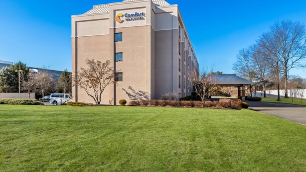 A Comfort Inn Suites building with a flat facade, a parking lot, and a well-maintained lawn.