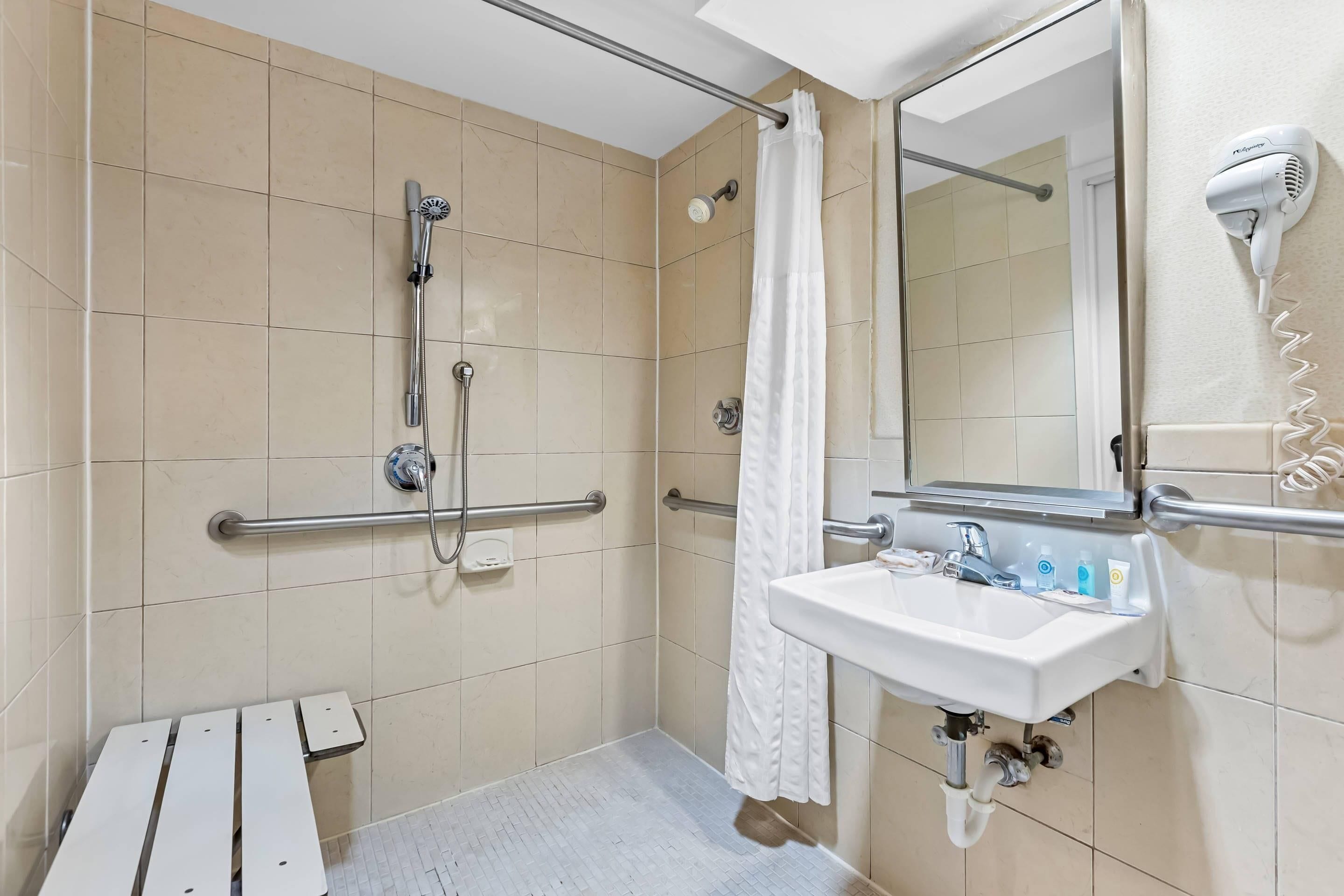 A bathroom with a shower, a sink, a mirror, and a hairdryer.