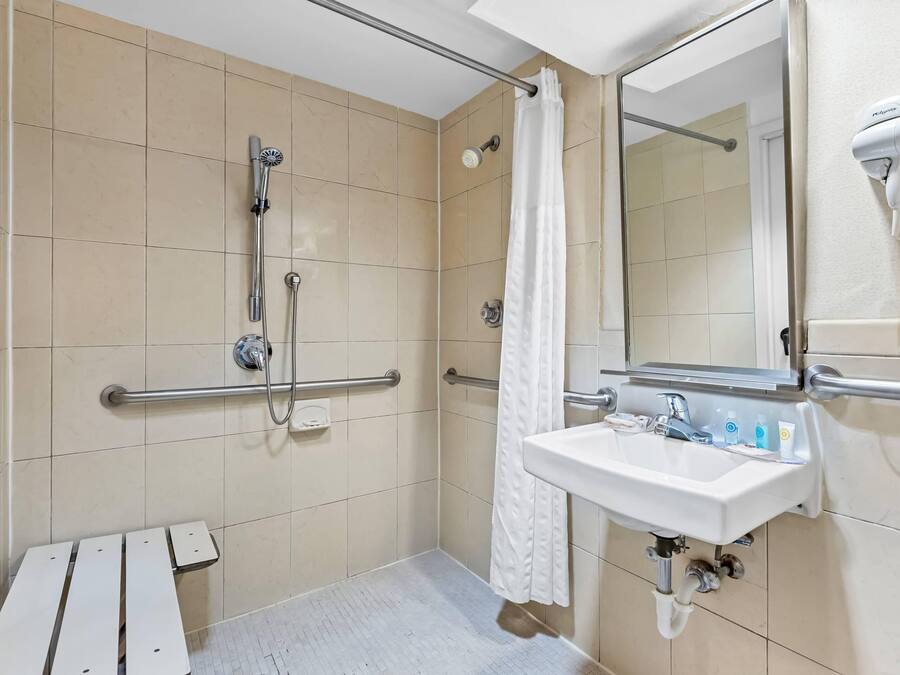 A bathroom with a shower, a sink, a mirror, and a hairdryer.