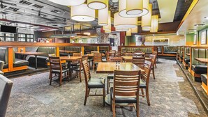 L'intérieur d'un restaurant avec des banquettes, des tables et des lampes suspendues.