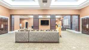 Un hall d’hôtel spacieux, doté d’un grand espace salon, d’un téléviseur à écran plat et d’un comptoir d’accueil.