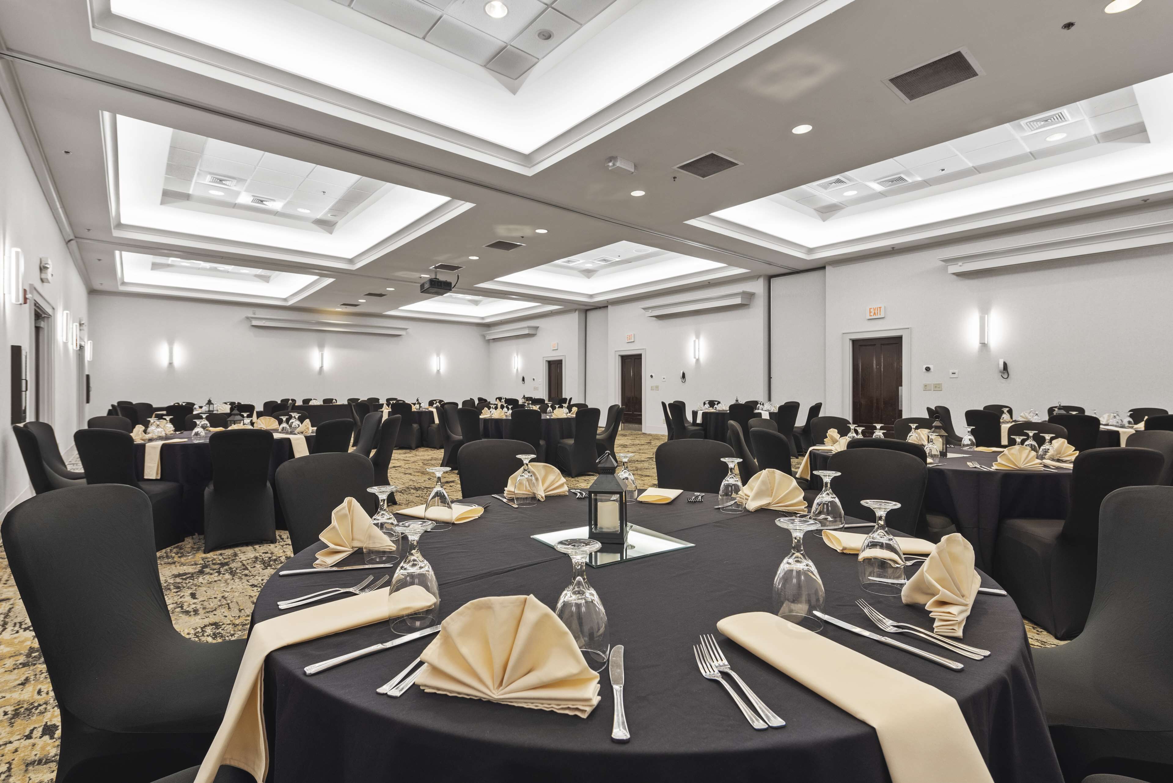 A conference room with round tables, black chairs, and a carpeted floor.