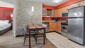 A hotel room with a bed, a dining table with chairs, a kitchen area with a refrigerator, microwave, stove, and cabinets. - MainStay Suites Appleton Airport - Fox River Mall Area (Appleton)
