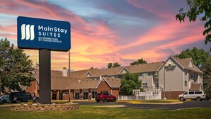 A MainStay Suites hotel with a brick facade, multiple windows, and a parking lot. - MainStay Suites Appleton Airport - Fox River Mall Area (Appleton)