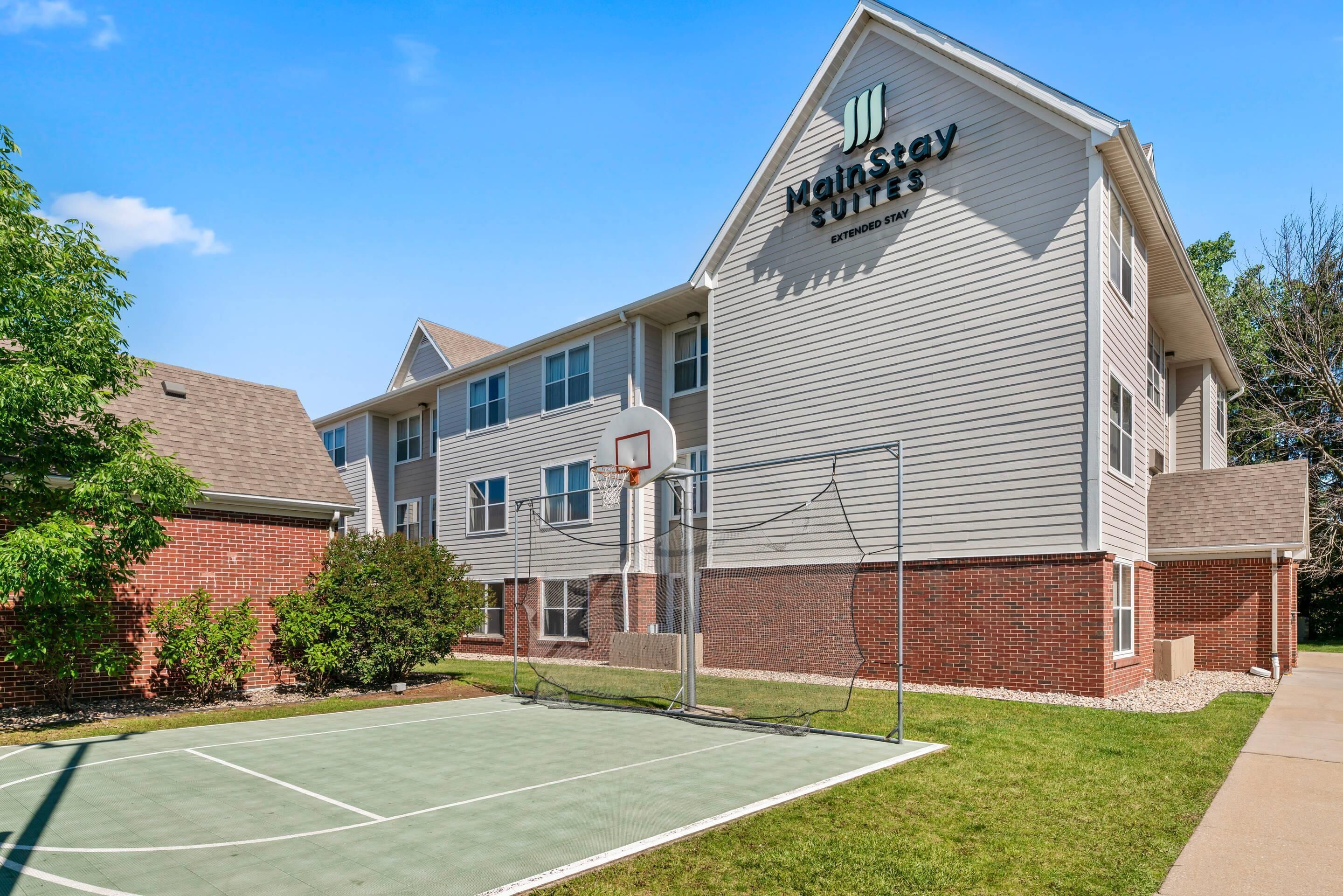 A MainStay Suites building with a basketball court in front.